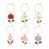 Custom flower-shaped wine glass charms featuring rose, daisy, lily, tulip, cherry blossom, and hydrangea designs with gold-plated metal outlines and enamel colors.
