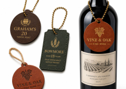 Multiple custom leather wine bottle tags displayed alongside a wine bottle