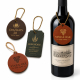 Multiple custom leather wine bottle tags displayed alongside a wine bottle