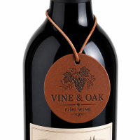 Custom debossed printed logo round leather wine bottle tag hanging from a wine bottle neck