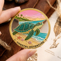Hand holding a round custom sea turtle metal souvenir with transparent imitation hard enamel, UV-printed coastal artwork, and gold-plated details.